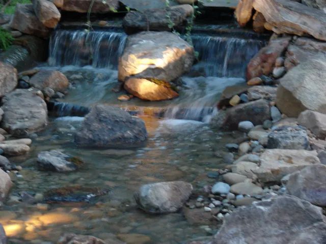 Small waterfall feature with rocks and clear water.