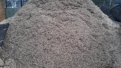 Pile of light brown wood chips outdoors.