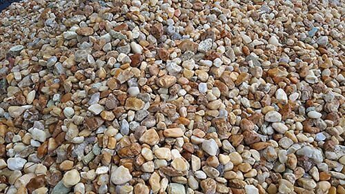 Pile of small, rounded beige, brown, and gray pebbles.