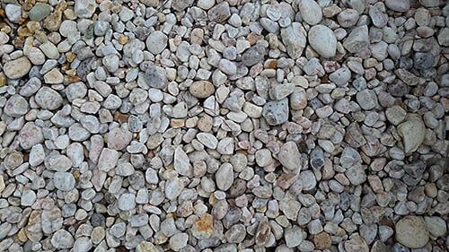 Close-up of small, light-colored pebbles, varying in shape and size.