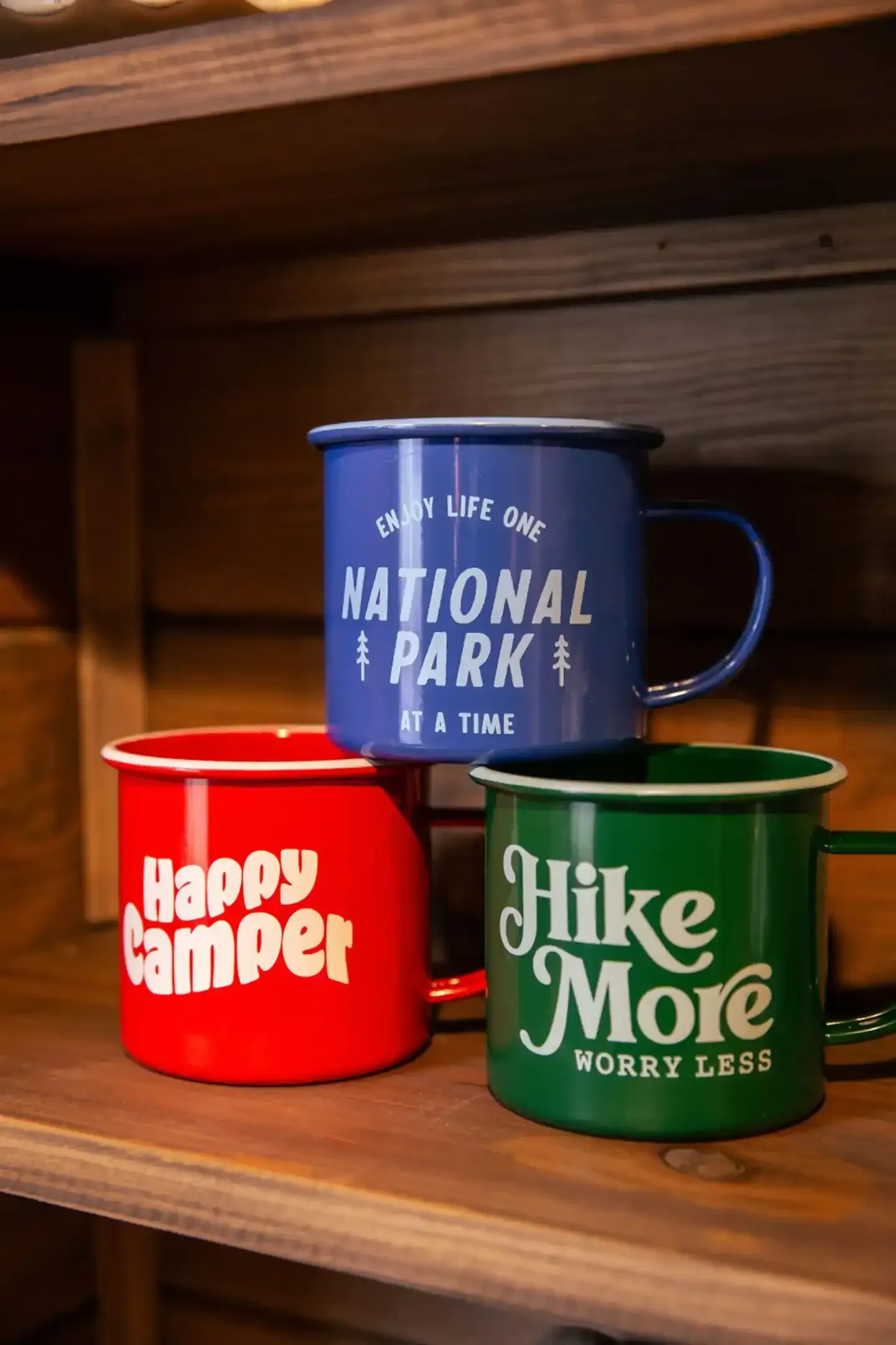 Three coffee mugs are sitting on a wooden shelf.