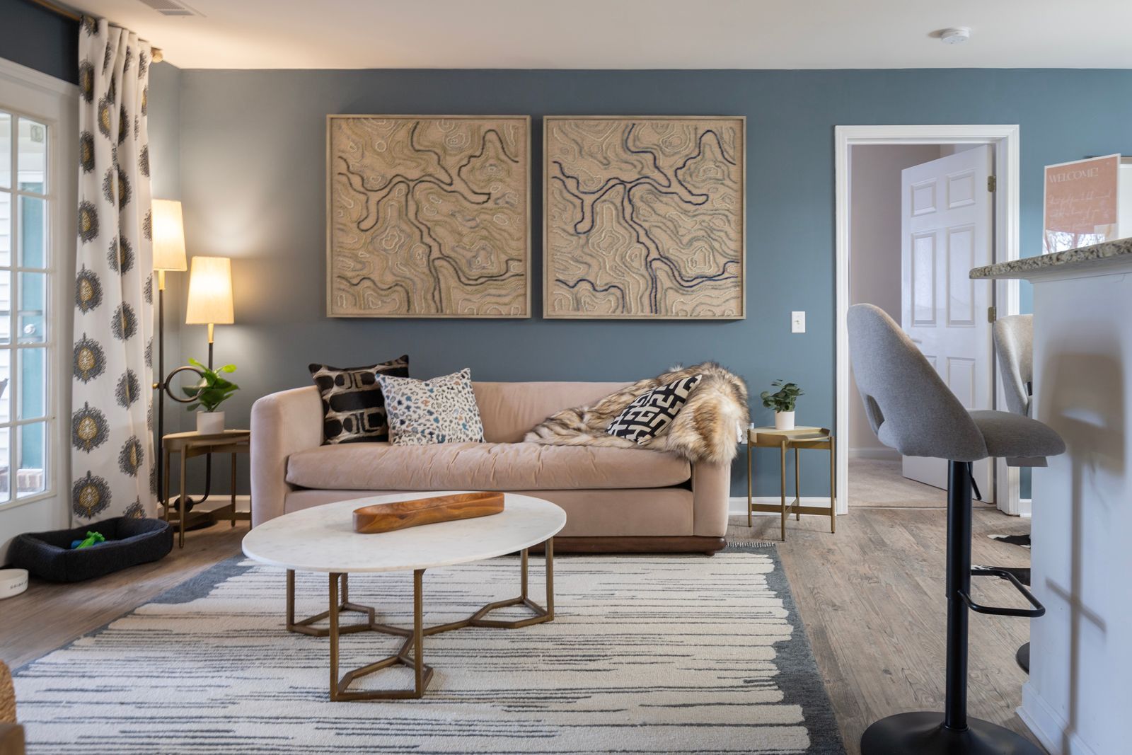 A living room with a couch , coffee table , and two paintings on the wall.