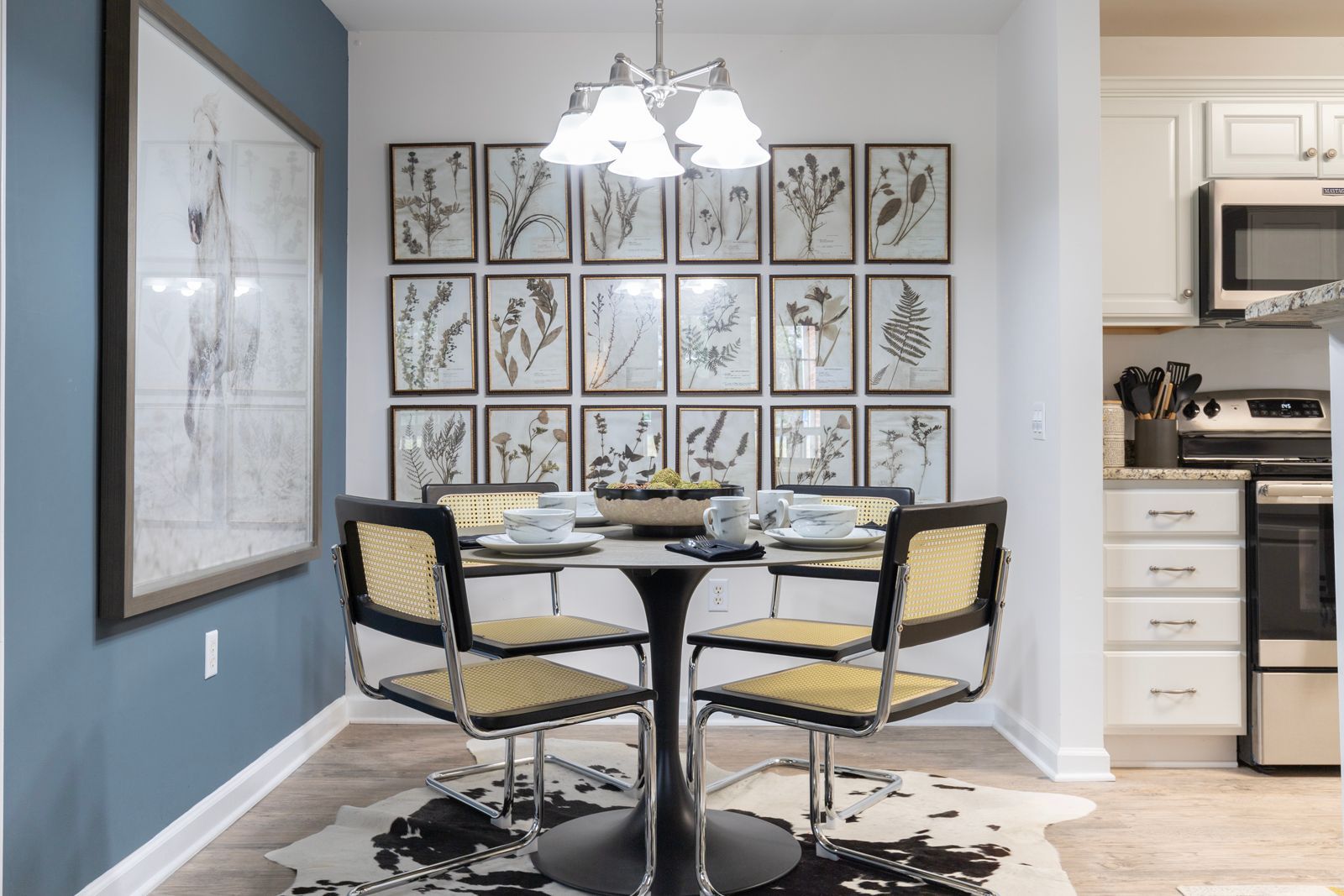 A dining room with a table and chairs and a wall with pictures on it.