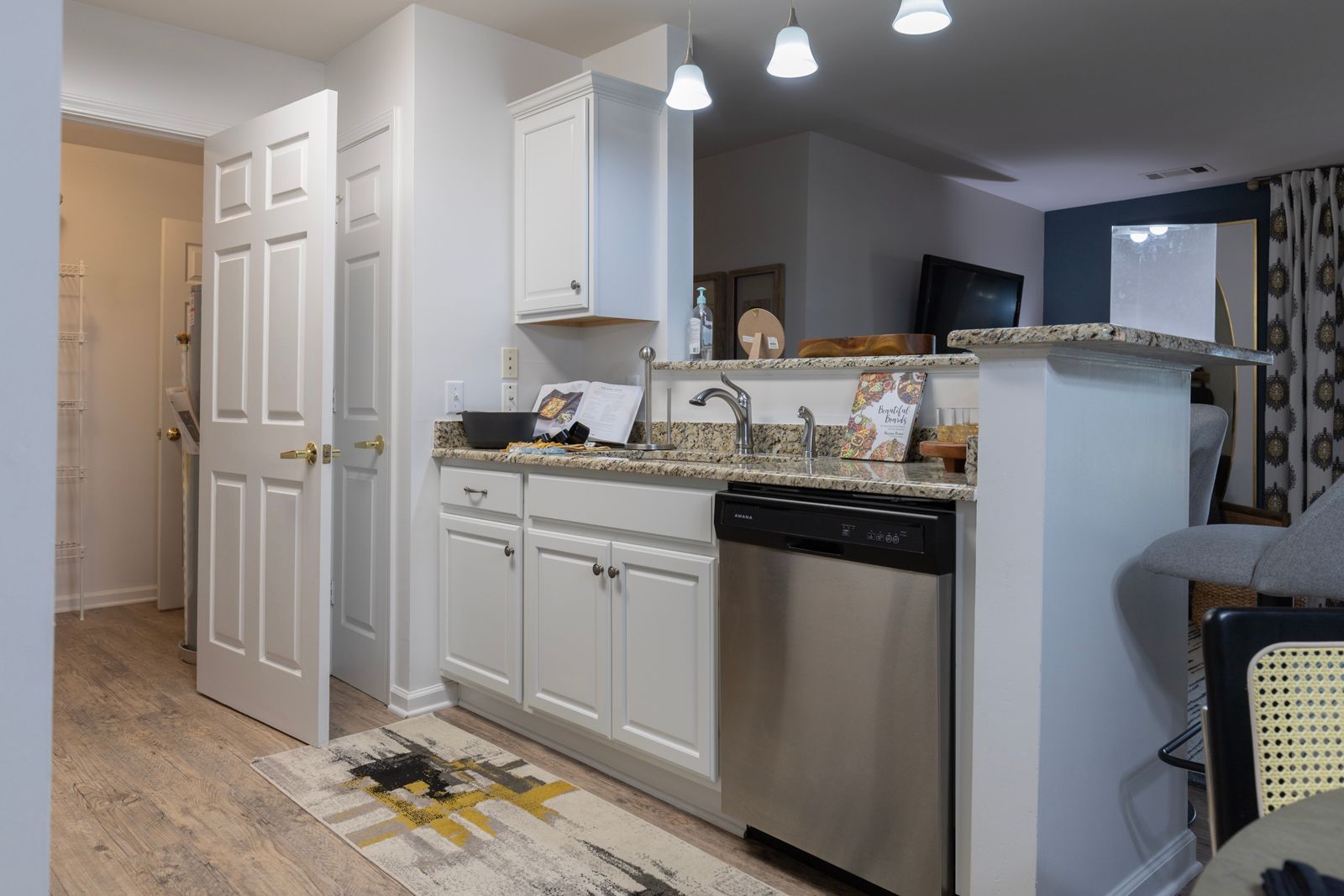 A kitchen with white cabinets , stainless steel appliances , and granite counter tops.