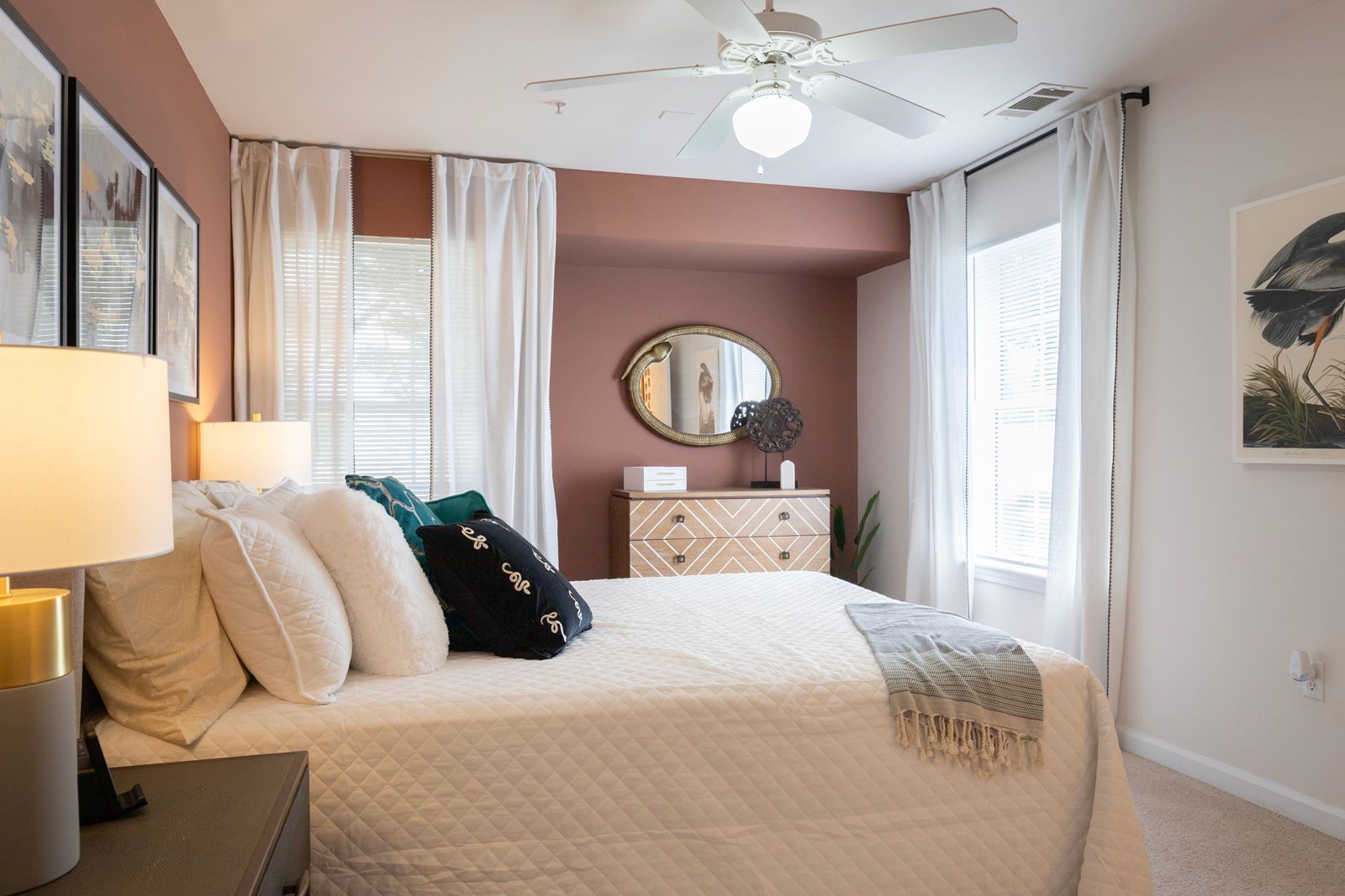 A bedroom with a bed , dresser , mirror and ceiling fan.