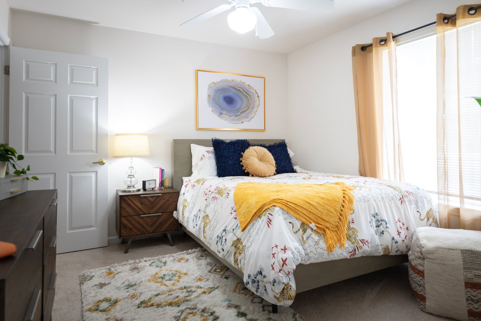 A bedroom with a bed , nightstand , dresser and ceiling fan.