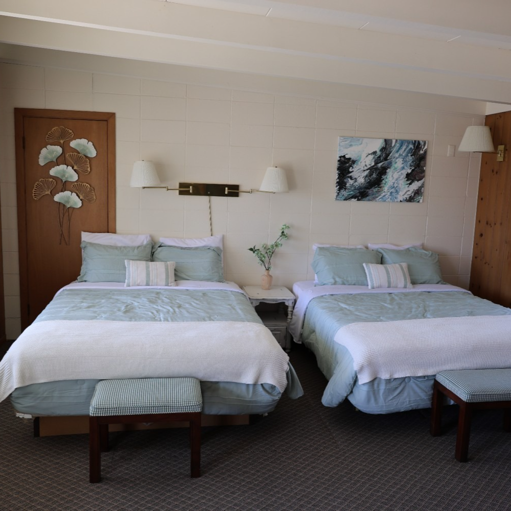 A hotel room with two beds and a painting on the wall