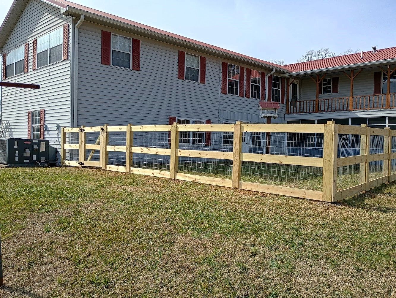 A wooden fence is in front of a large house.
