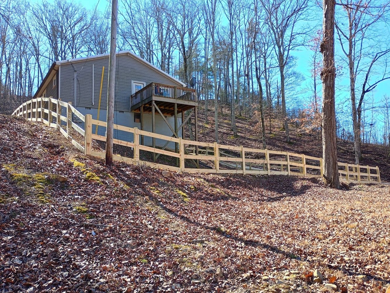 A wooden fence surrounds a house in the woods.