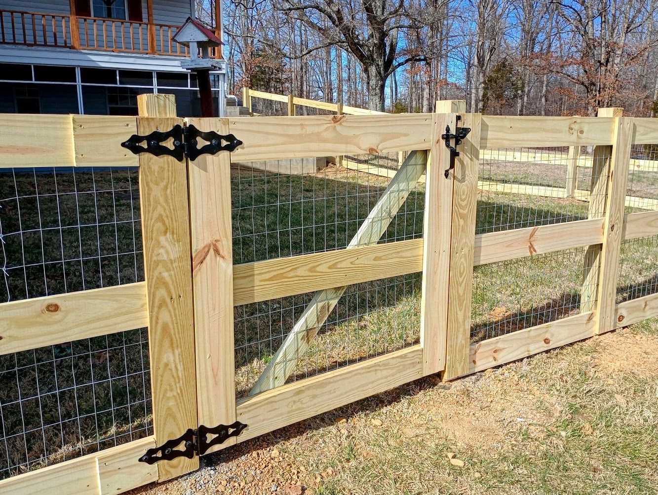 A wooden fence with a chicken wire fence behind it.