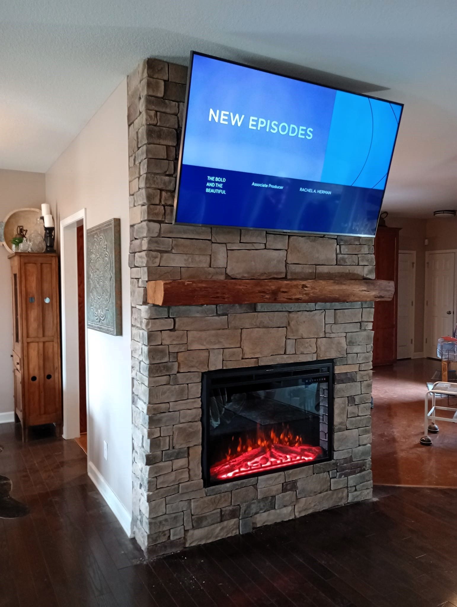 A living room with a fireplace and a flat screen tv on the wall.