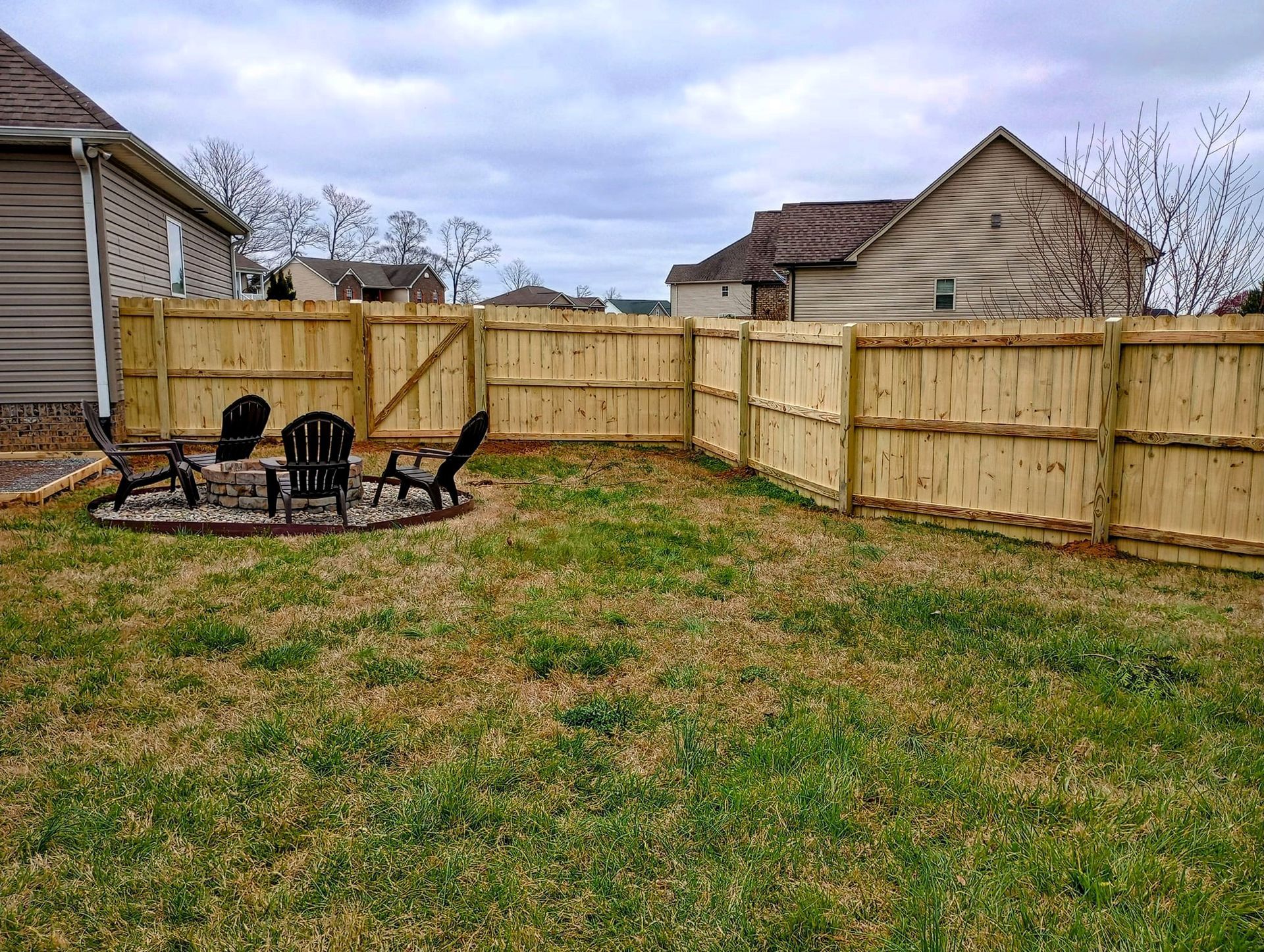 A backyard with a wooden fence and a fire pit.