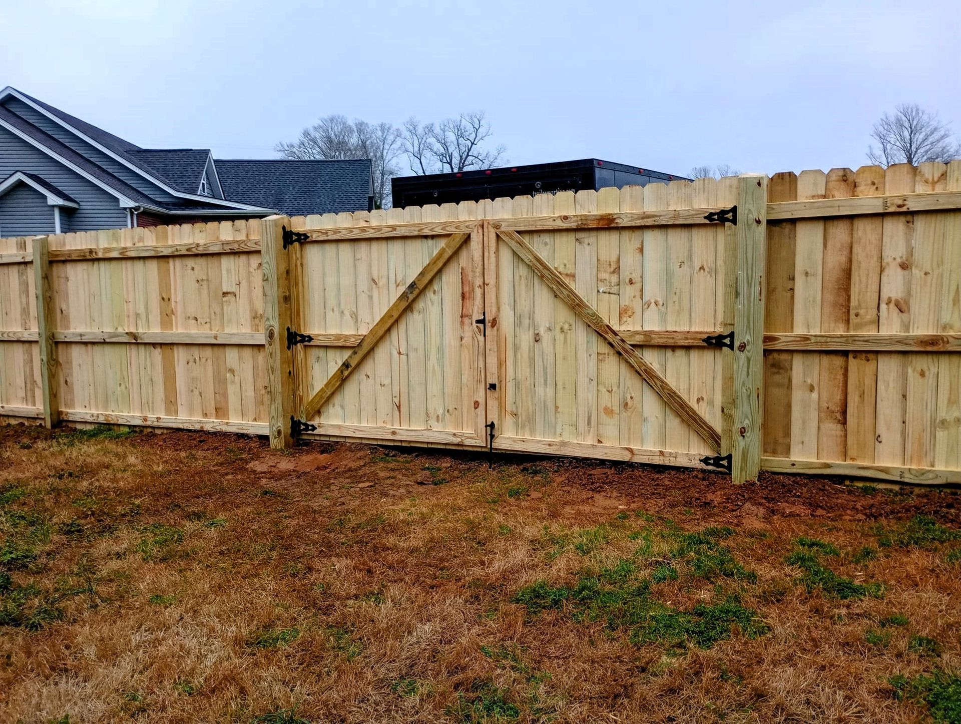 A wooden fence with a gate in the backyard of a house.