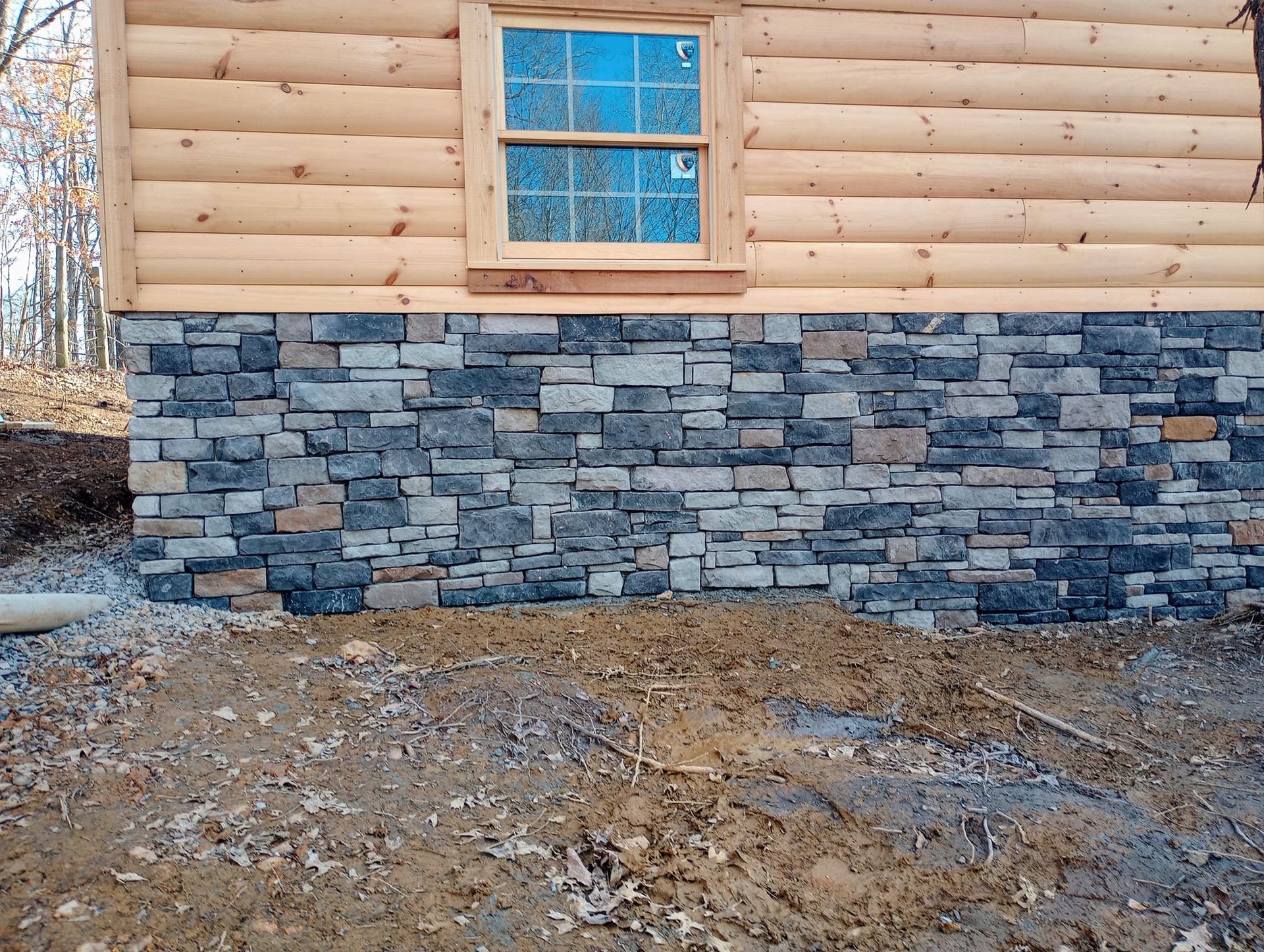 A log cabin with a stone wall and a window