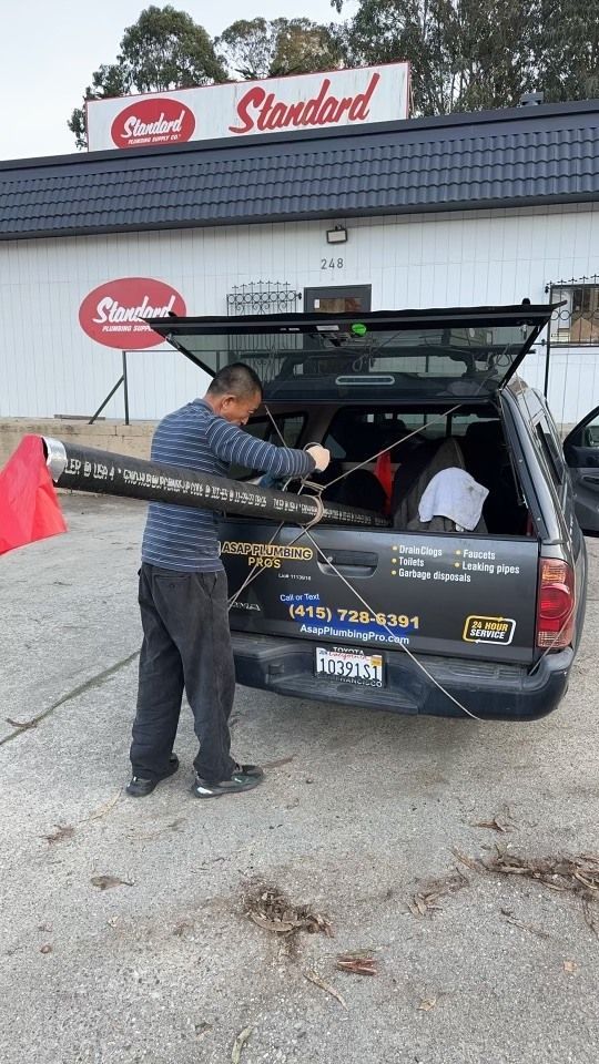 A man is loading a carpet into the back of a truck.
