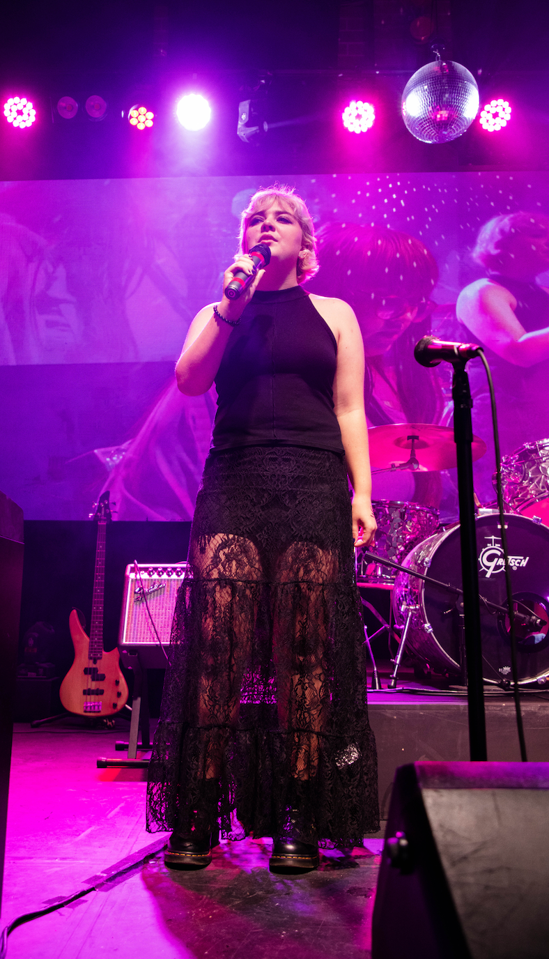 A woman is singing into a microphone on a stage.