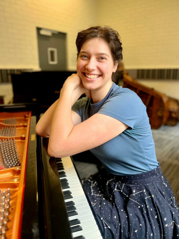 A woman is sitting at a piano and smiling.