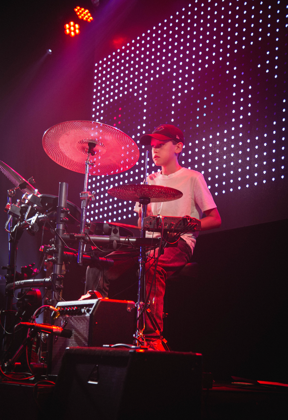 A man is playing drums on a stage in front of a skull.
