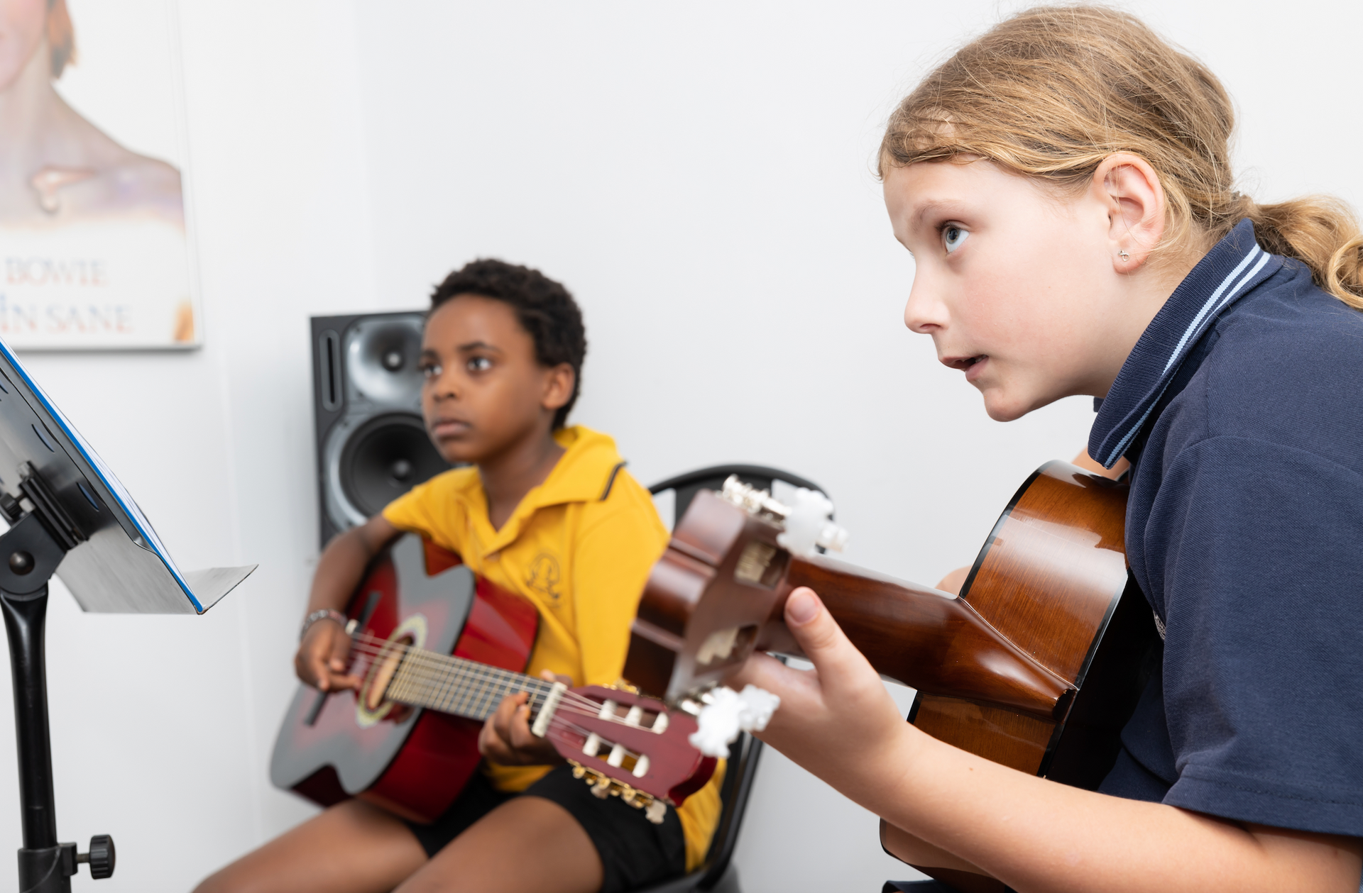 A boy and a girl are playing guitars in a room.