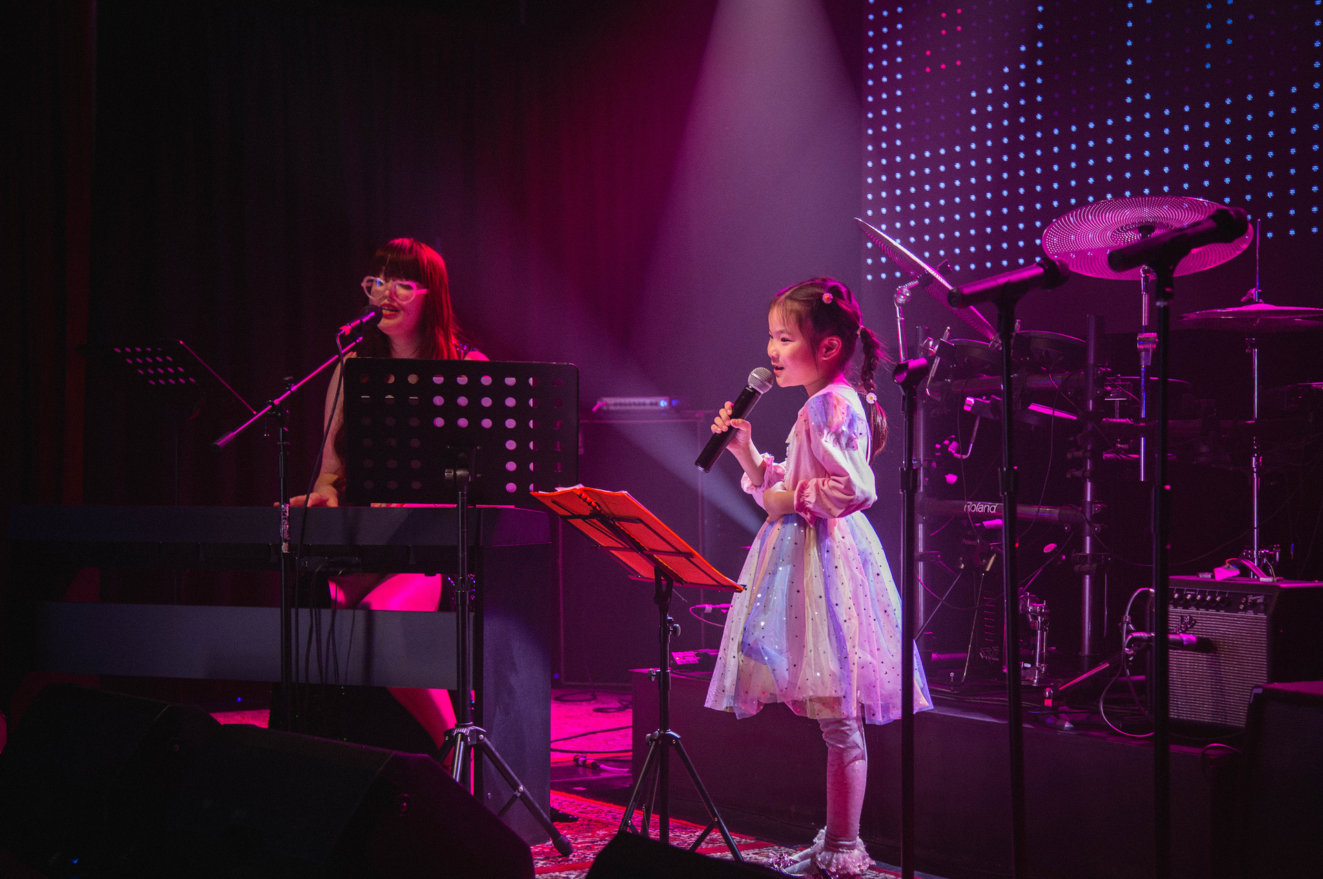A young girl is singing into a microphone on a stage.