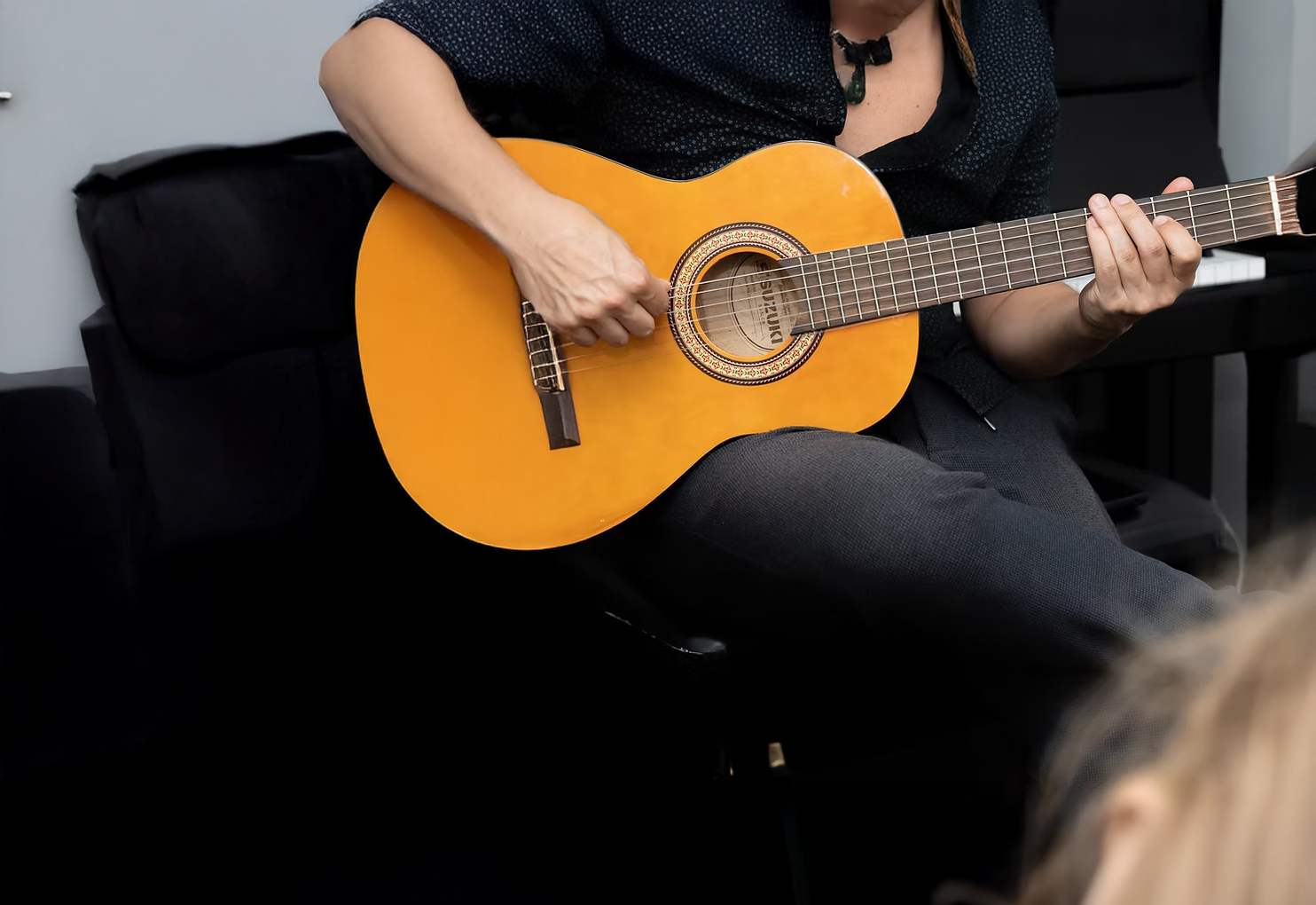 A woman is sitting on a couch playing an acoustic guitar
