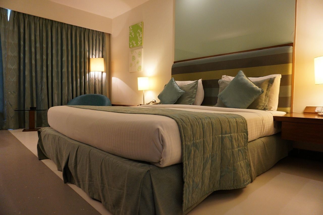 Hotel bedroom with a large bed, teal accents, and warm lighting.