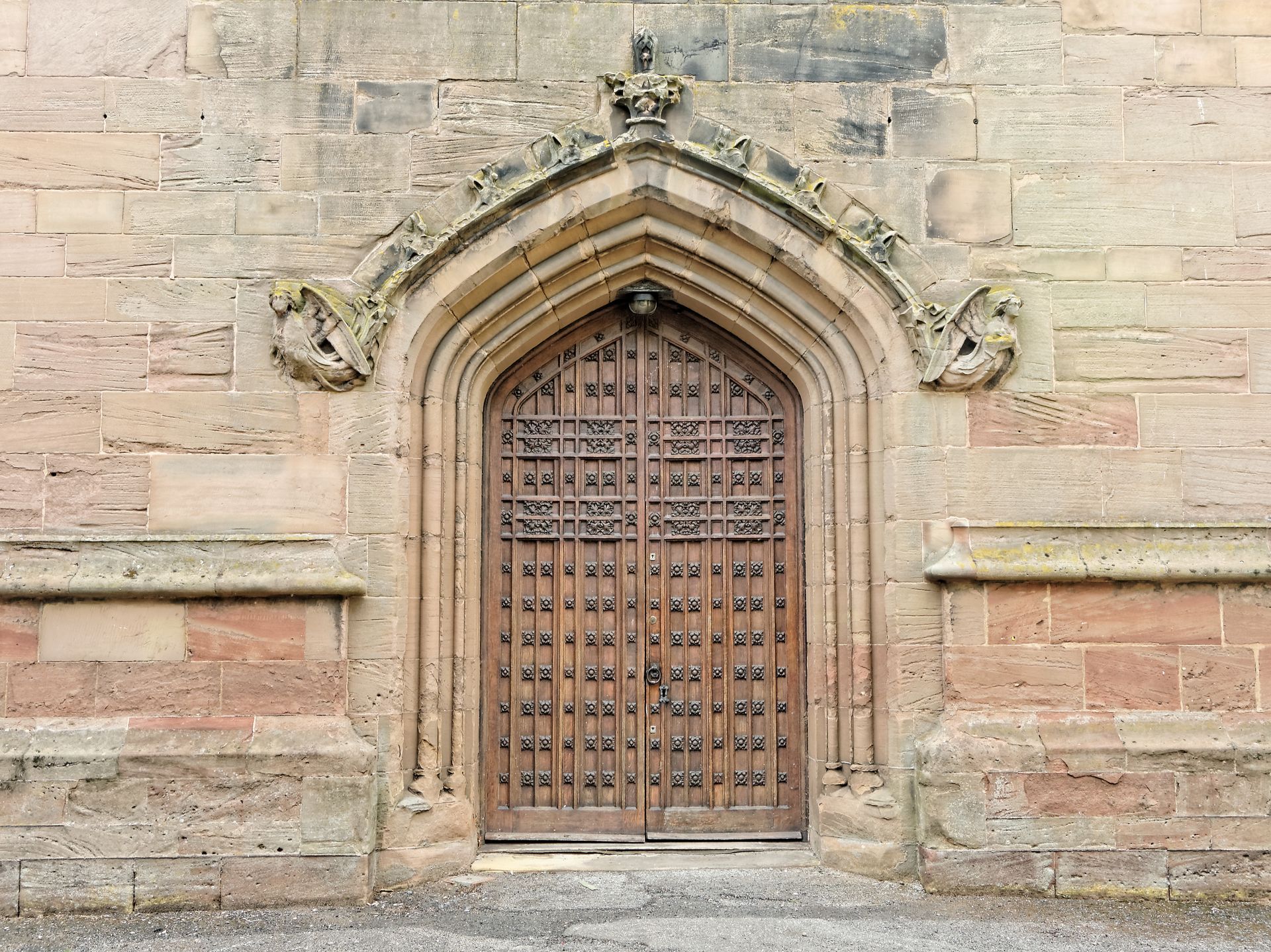 Wooden church door with arched entrance, stone walls, and decorative carvings.
