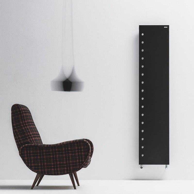 Una poltrona moderna con un motivo a quadri scuri è posizionata accanto a un alto termosifone rettangolare nero su una parete bianca.