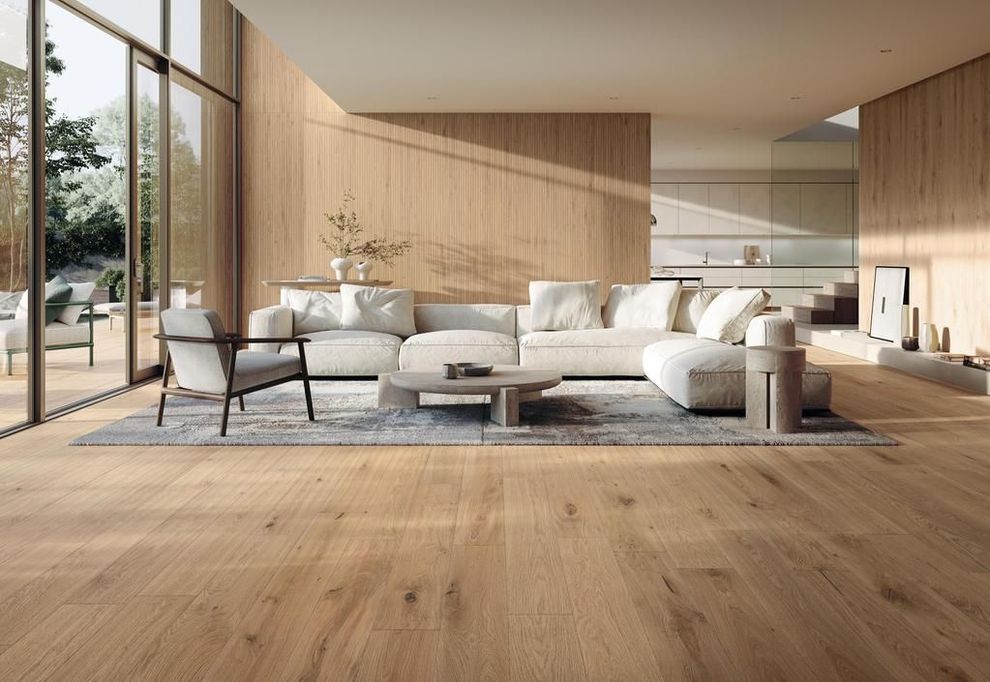 Un soggiorno moderno con pavimenti e pareti in legno chiaro, un divano angolare bianco e finestre a tutta altezza.