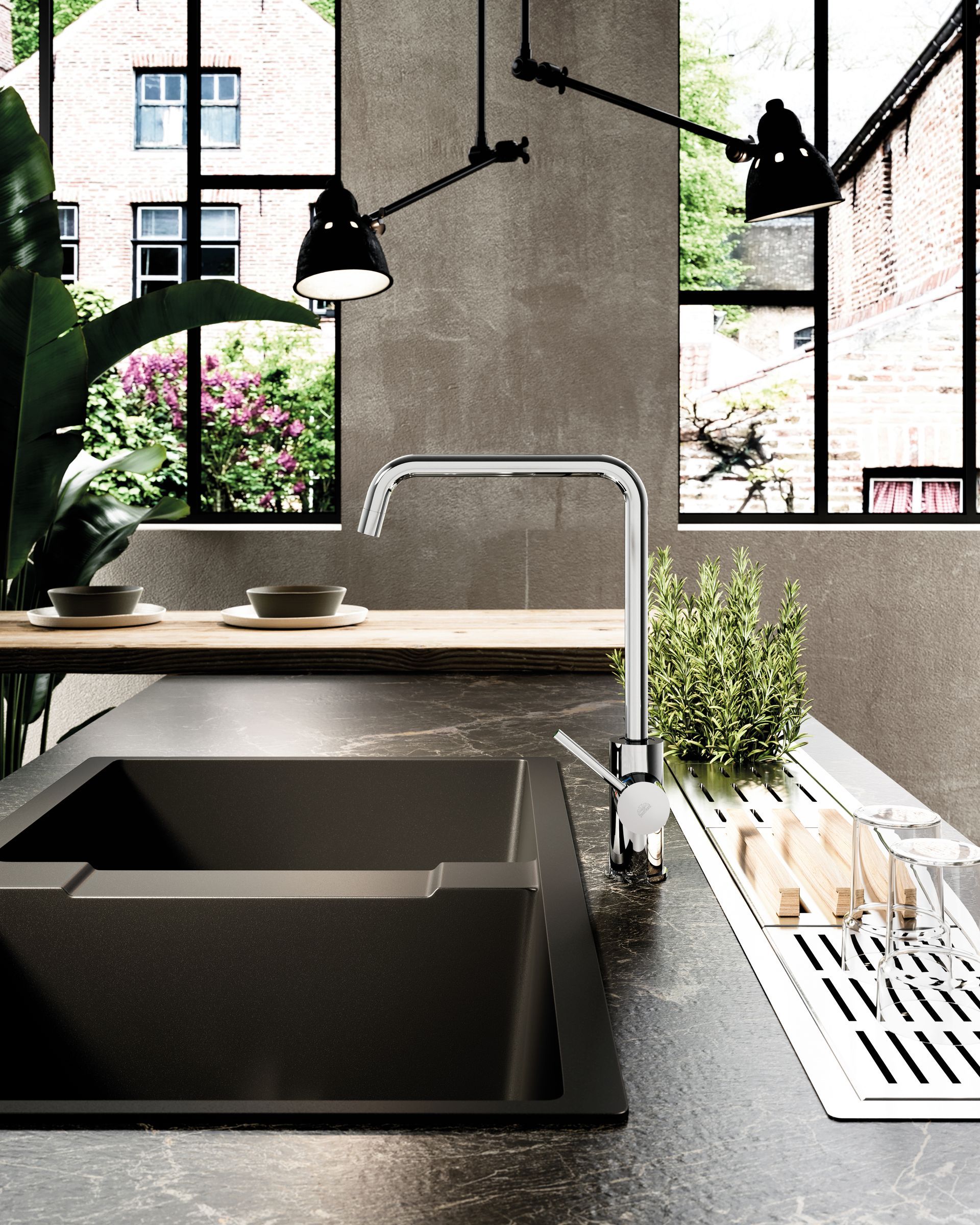 Un moderno lavello da cucina con rubinetto cromato incastonato in un piano di lavoro in pietra scura, visto di fronte a una finestra.