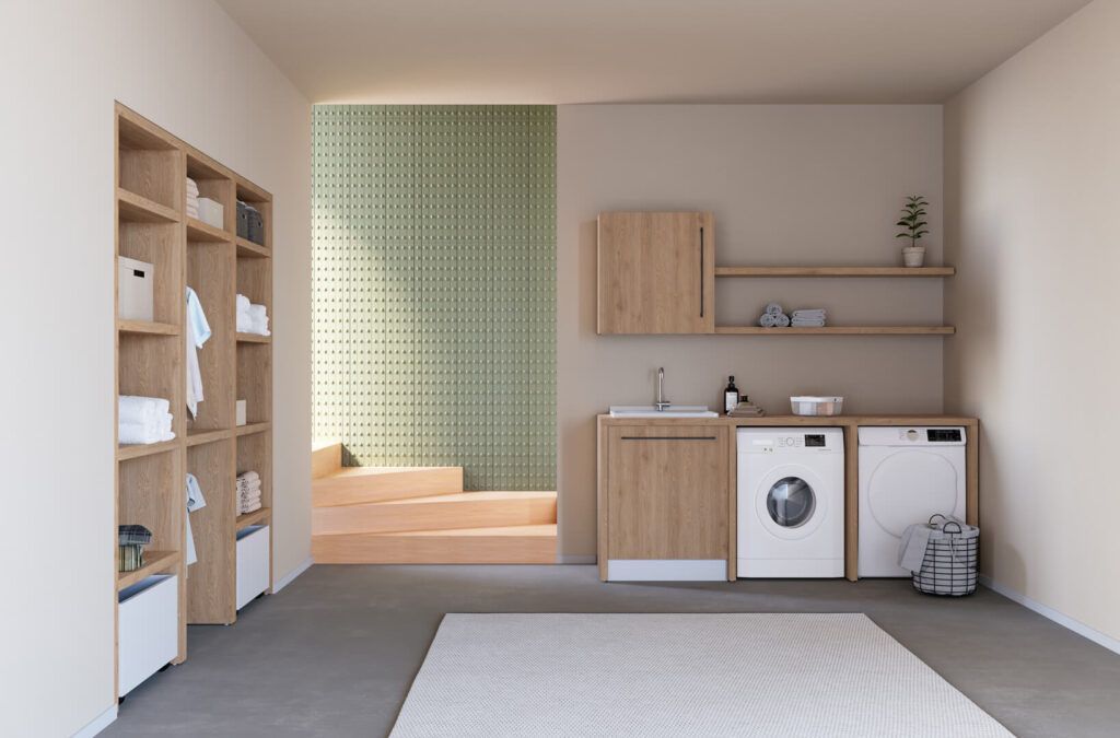 Una lavanderia con scaffalature in legno chiaro, un mobiletto coordinato con lavabo, due elettrodomestici bianchi e una parete rivestita di piastrelle verdi.
