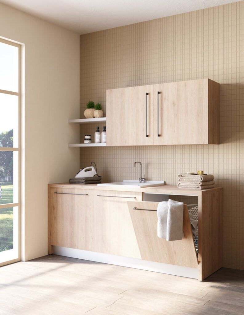 Un mobiletto da lavanderia in legno chiaro con lavello, ripiani a vista e un asciugamano appoggiato su un'anta aperta.
