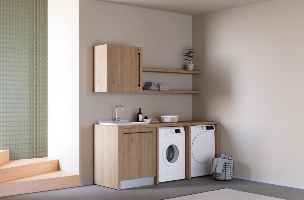 Una lavanderia con mobili in legno chiaro, due lavatrici bianche, un piccolo lavandino e due mensole su una semplice parete beige.