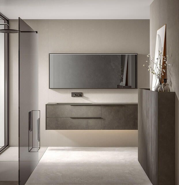 Un bagno minimalista con mobile lavabo sospeso grigio scuro, specchio abbinato, cabina doccia in vetro e pareti dai toni neutri.
