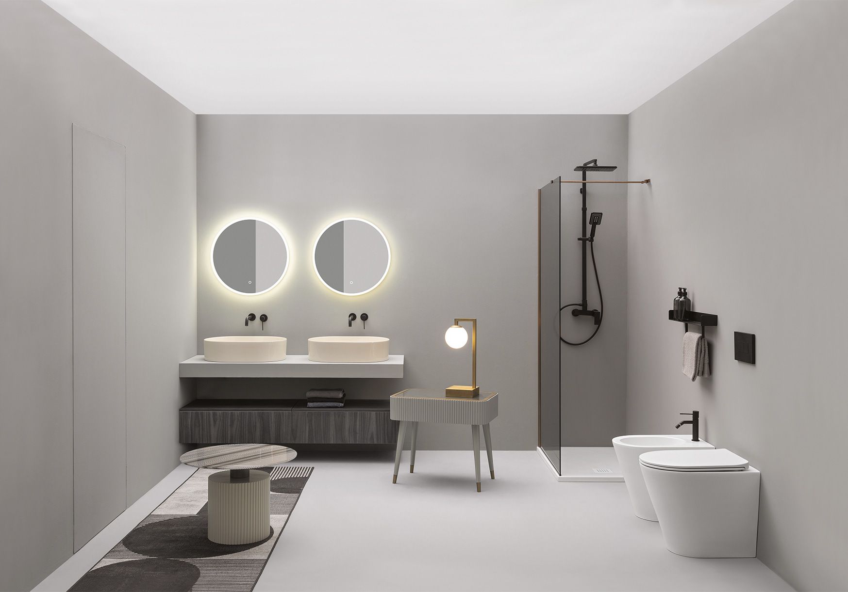 Un moderno bagno grigio è dotato di doppio lavabo con specchi rotondi retroilluminati, doccia con box in vetro, bidet e WC.