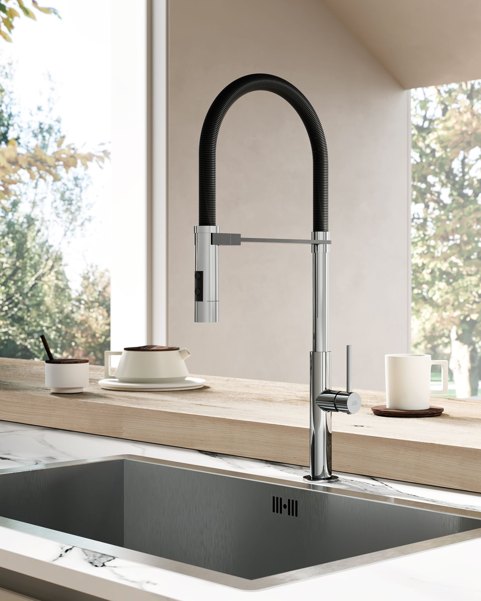 Un rubinetto da cucina cromato con un collo a spirale flessibile nero si erge sopra un lavello grigio scuro su un piano di lavoro in marmo.