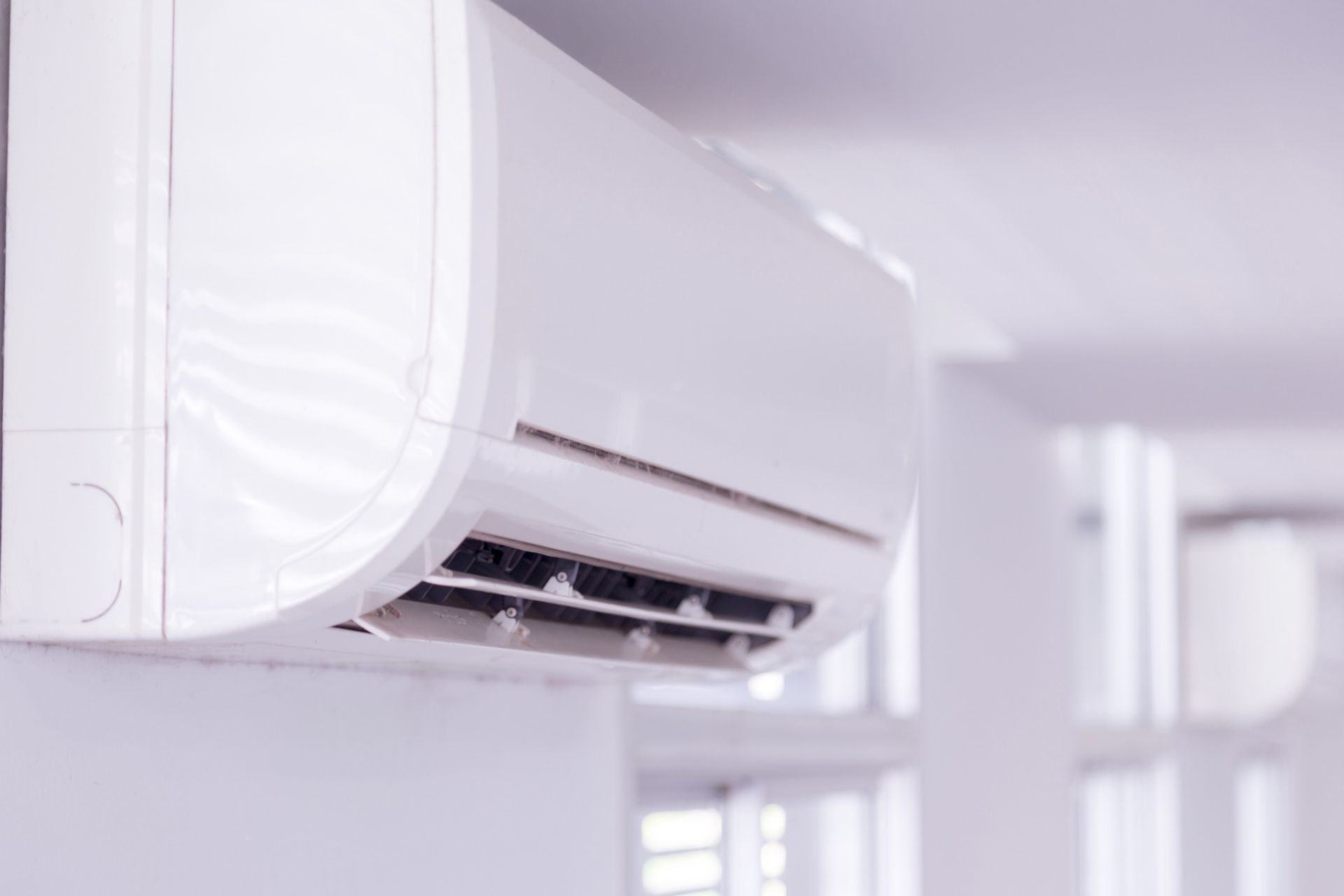 White, wall-mounted air conditioning unit in a bright room.