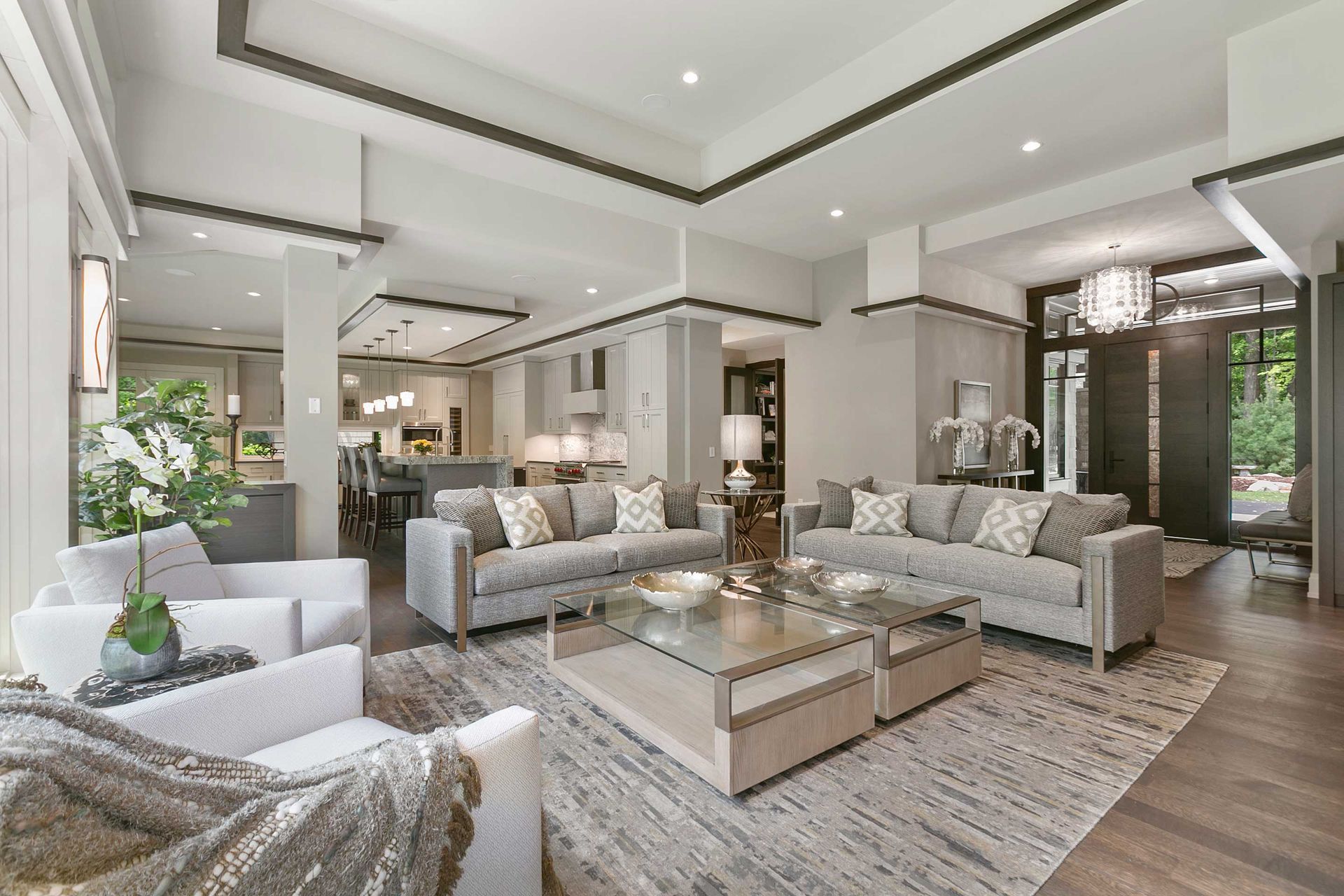 Elegant living room with gray sofas, glass coffee tables, and a patterned rug.