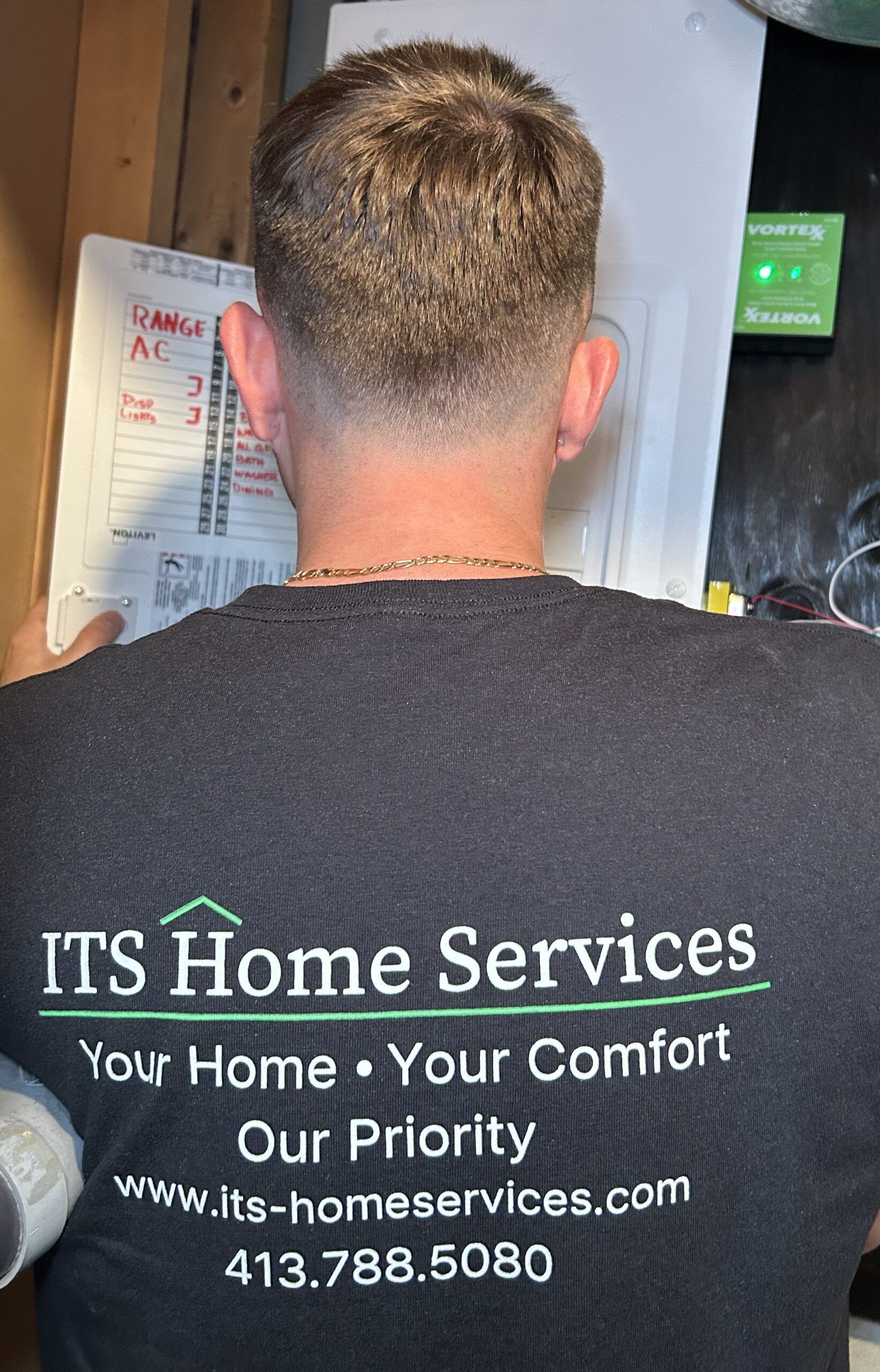 Man wearing an ITS Home Services shirt, looking at a panel.