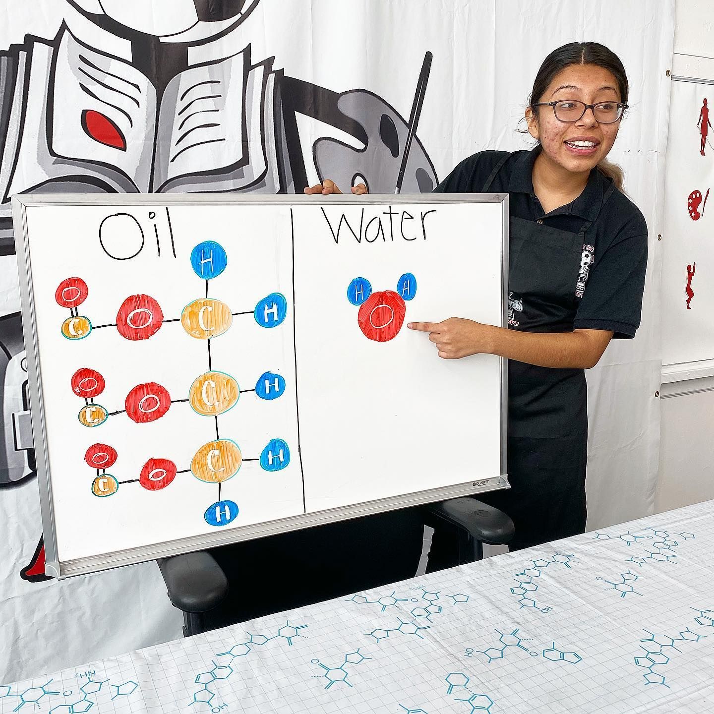 A woman is holding a white board that says oil and water