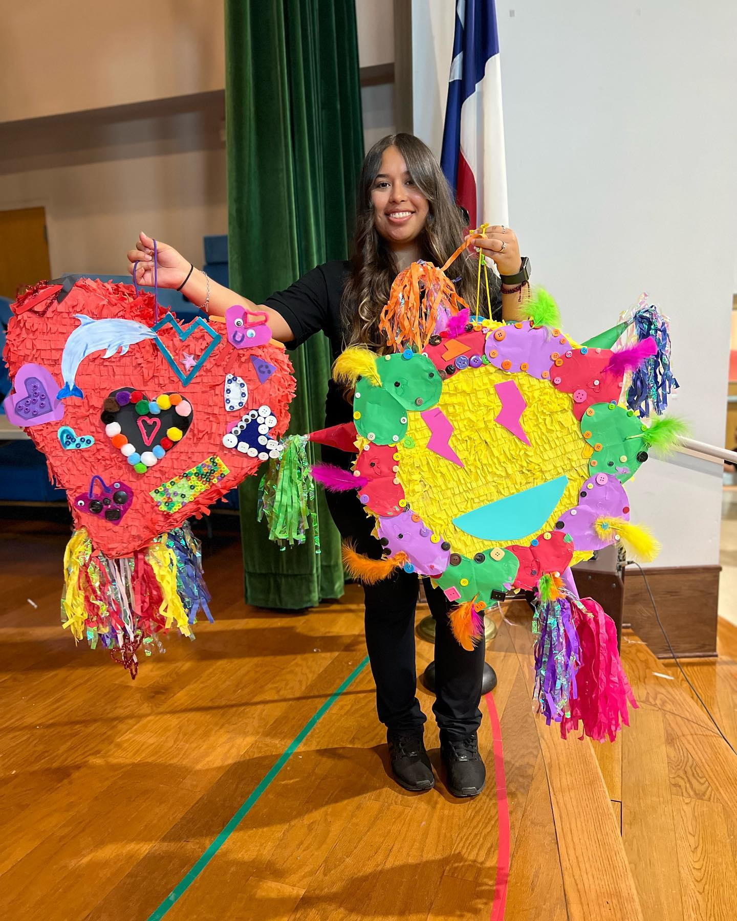 A woman is holding two colorful pinatas in her hands.