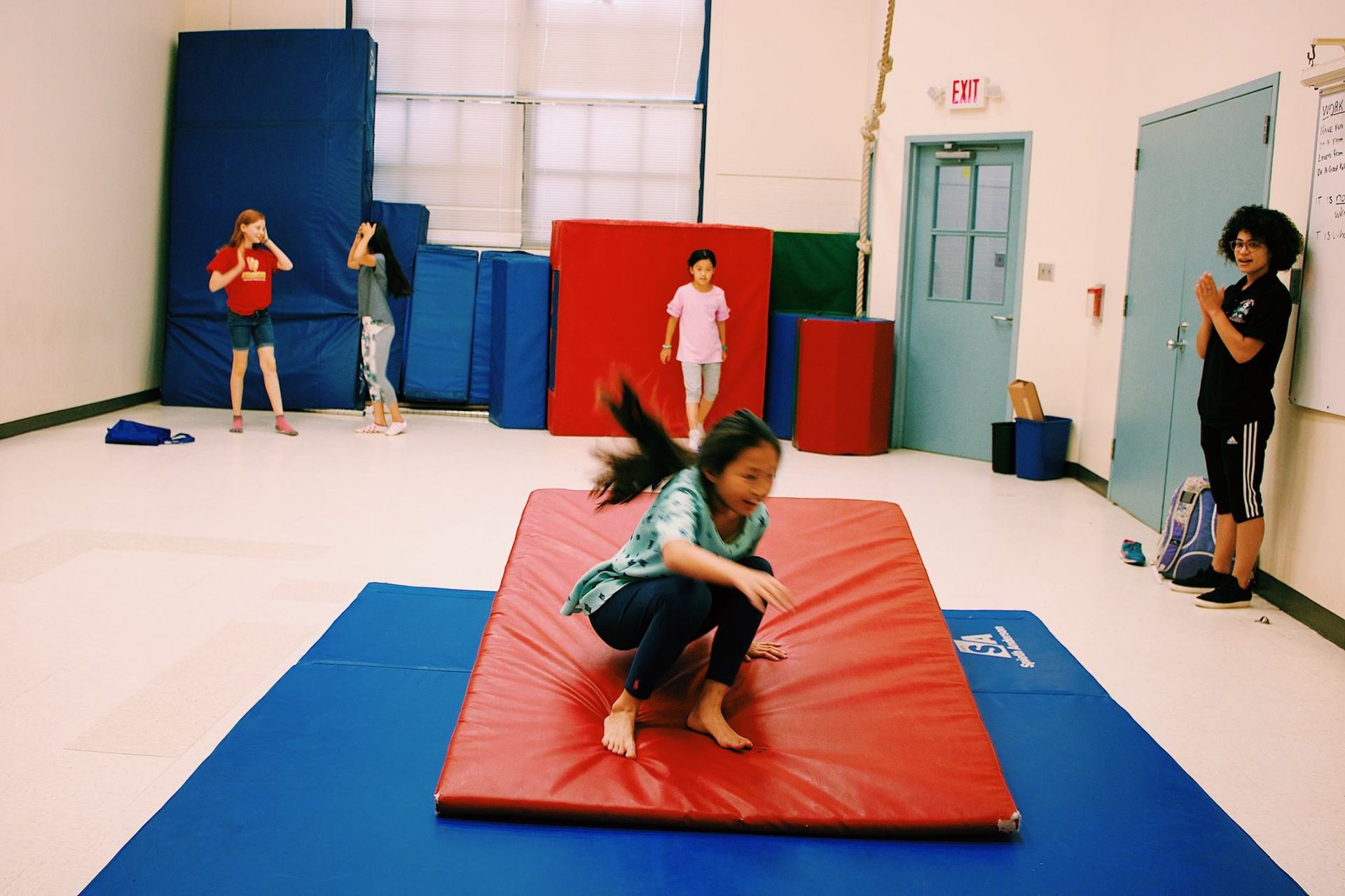 A girl is squatting on a mat in a gym