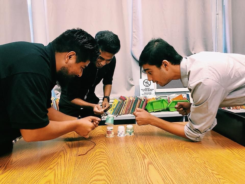Three men are working on a project on a wooden table.