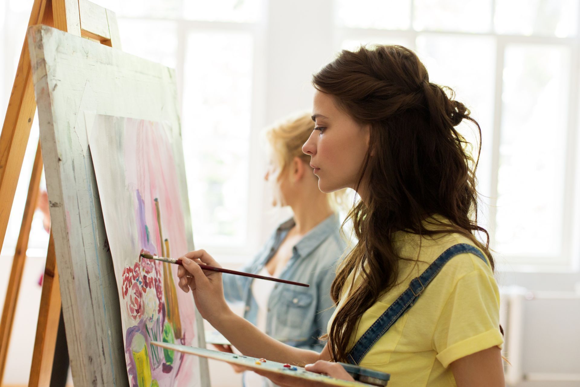 A woman is painting a picture on an easel.