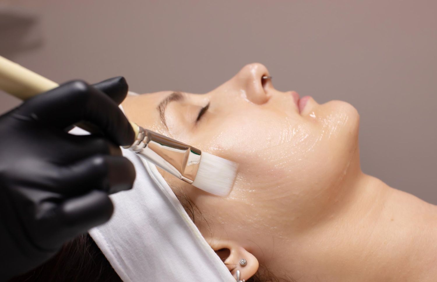 A woman is getting a facial treatment with a brush.