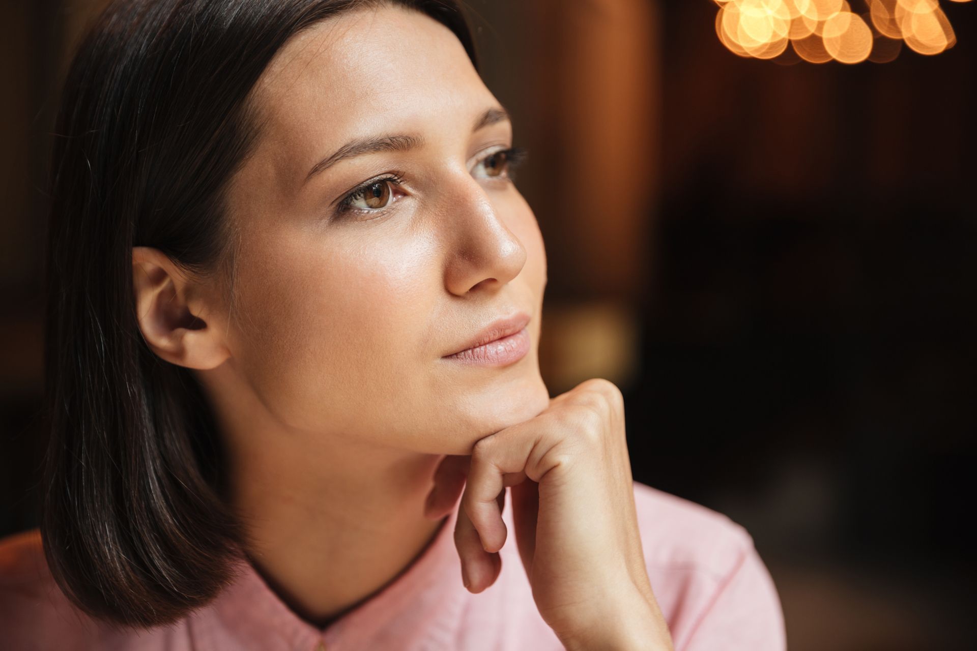 A close up of a woman 's face with her hand on her chin.
