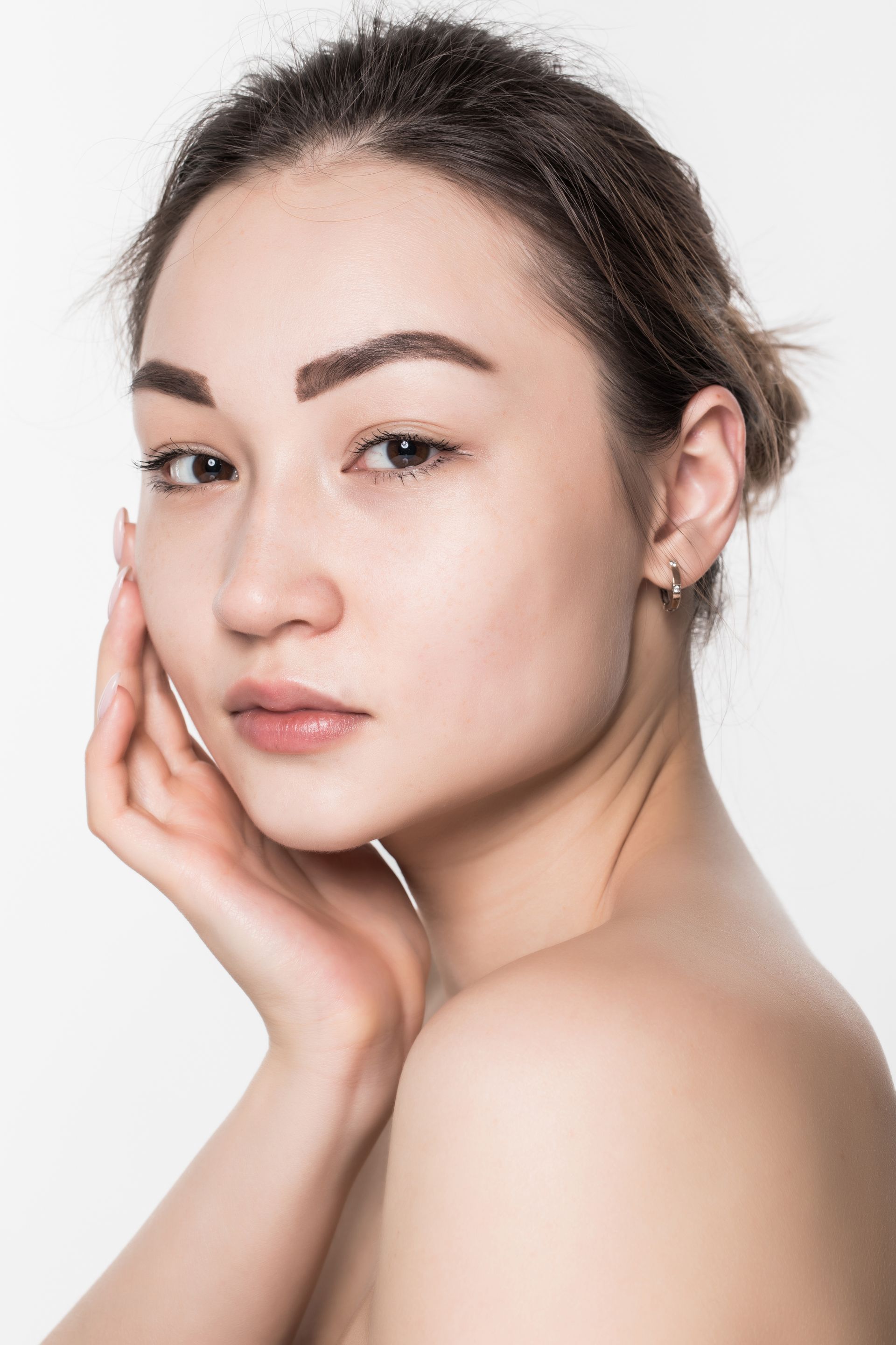 A woman is touching her face with her hand and looking at the camera.