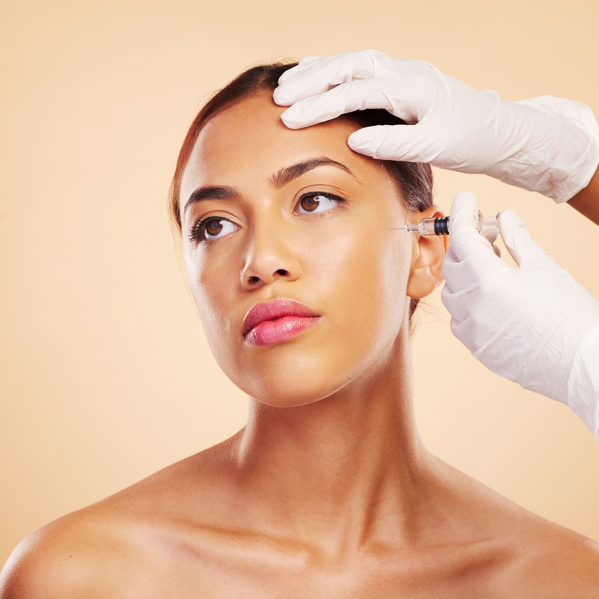 A woman is getting a botox injection in her forehead.