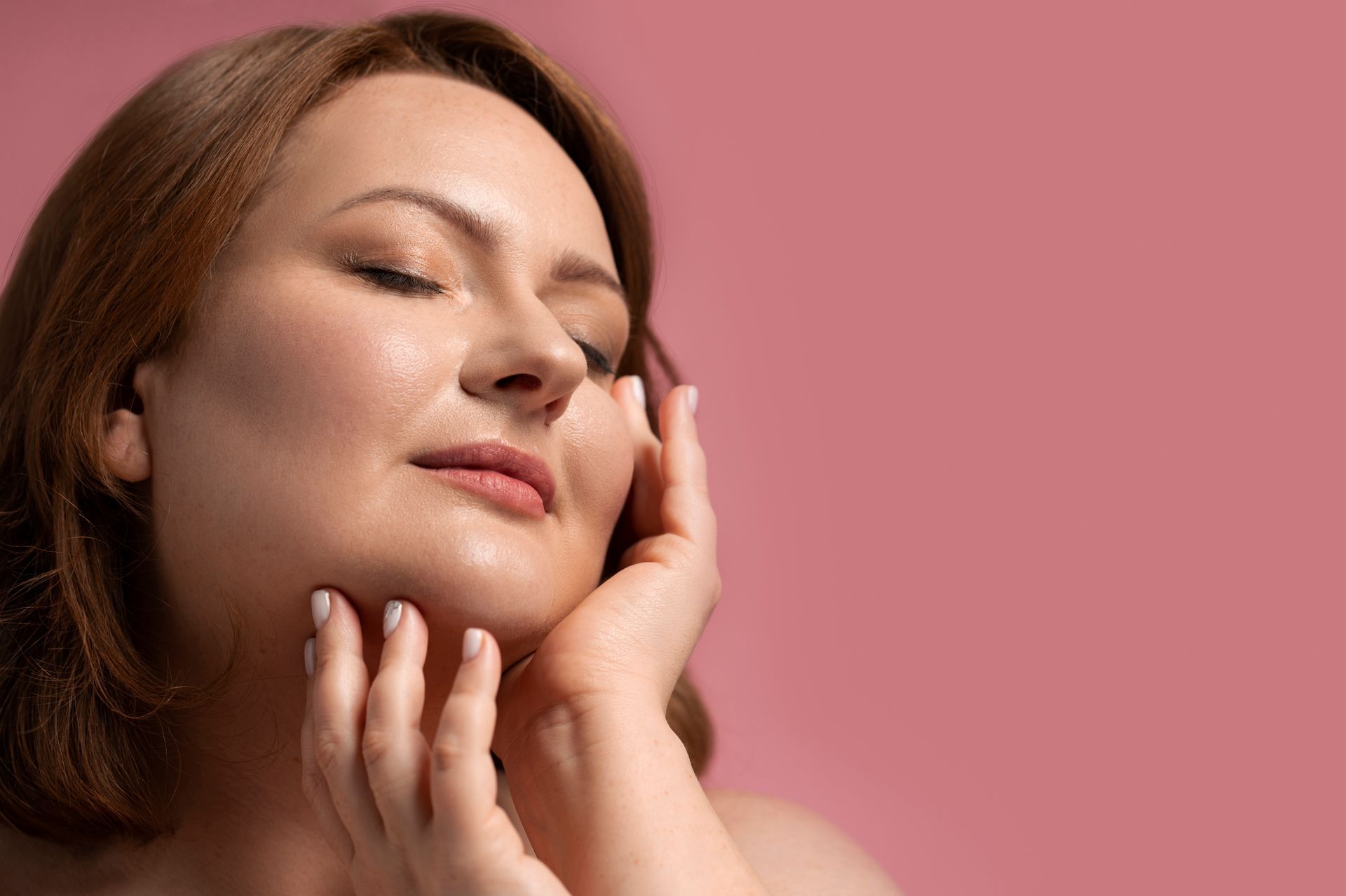 A woman with closed eyes touching her face with both hand