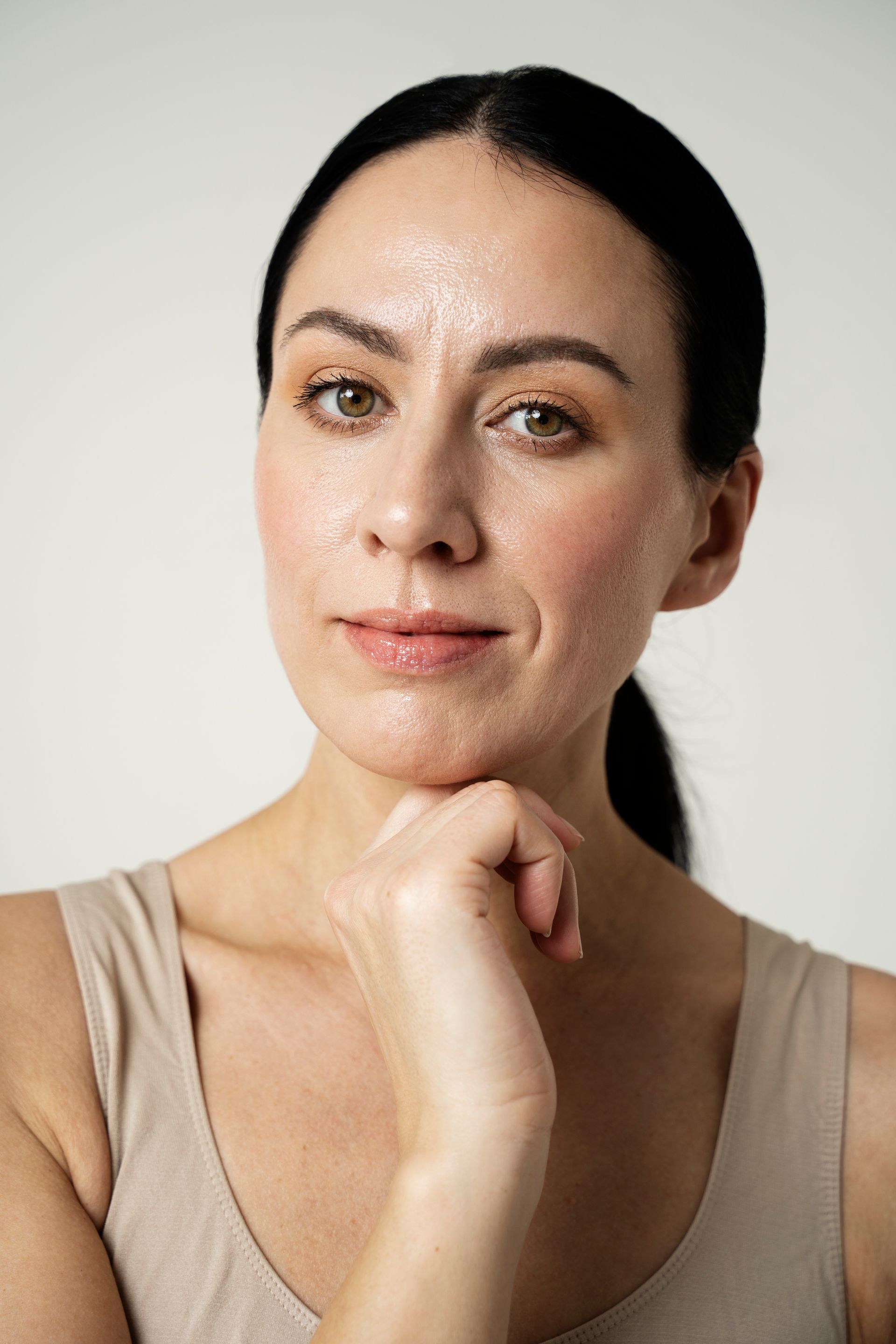 A close up of a woman 's face with her hand on her chin.